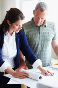 Two architects looking at blueprint and discussing a new project
